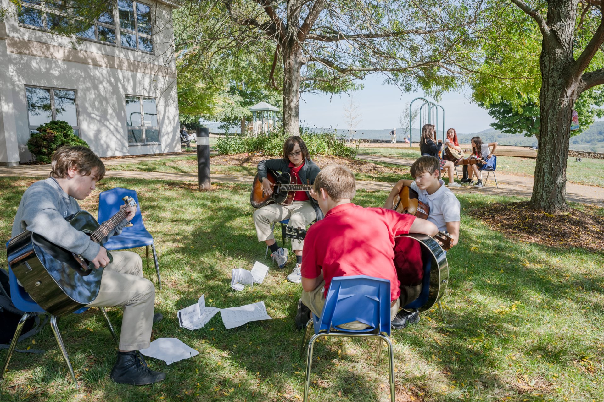 middle school students sitting outside playing guitars